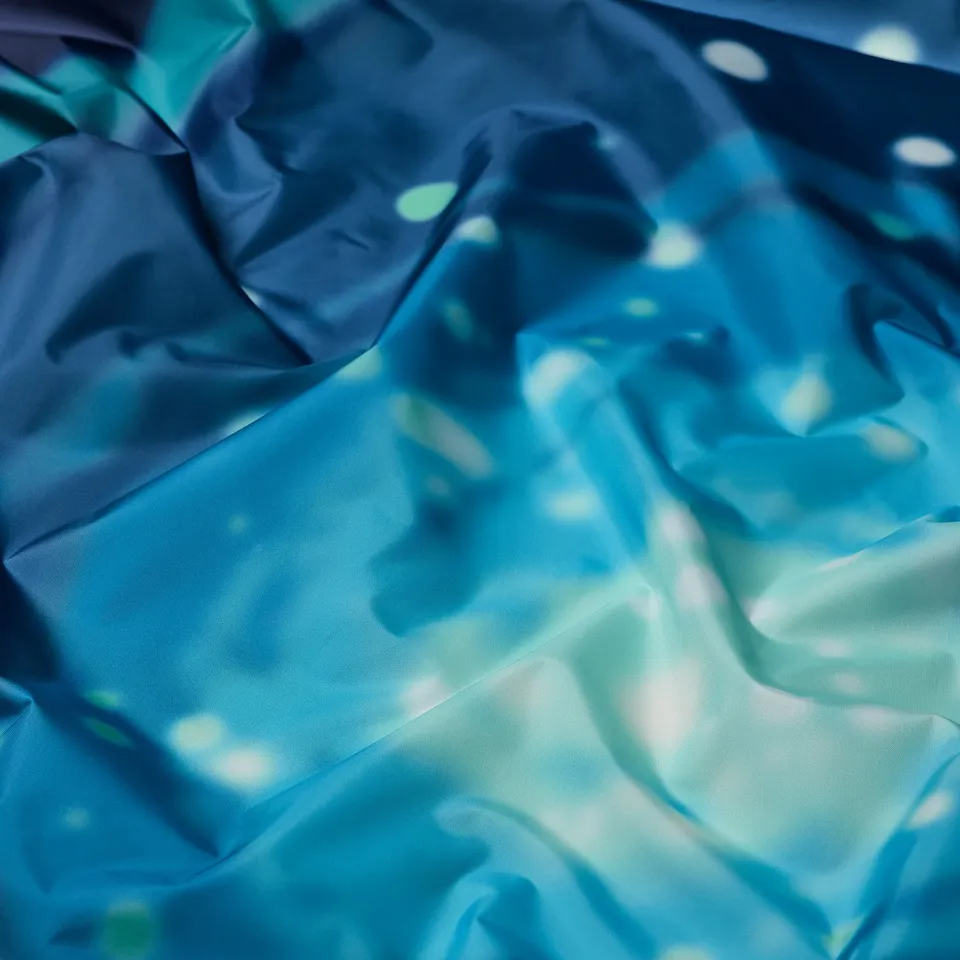 Close-up of shimmery, blue fabric with subtle sparkling pattern, showcasing its smooth texture and quality.
