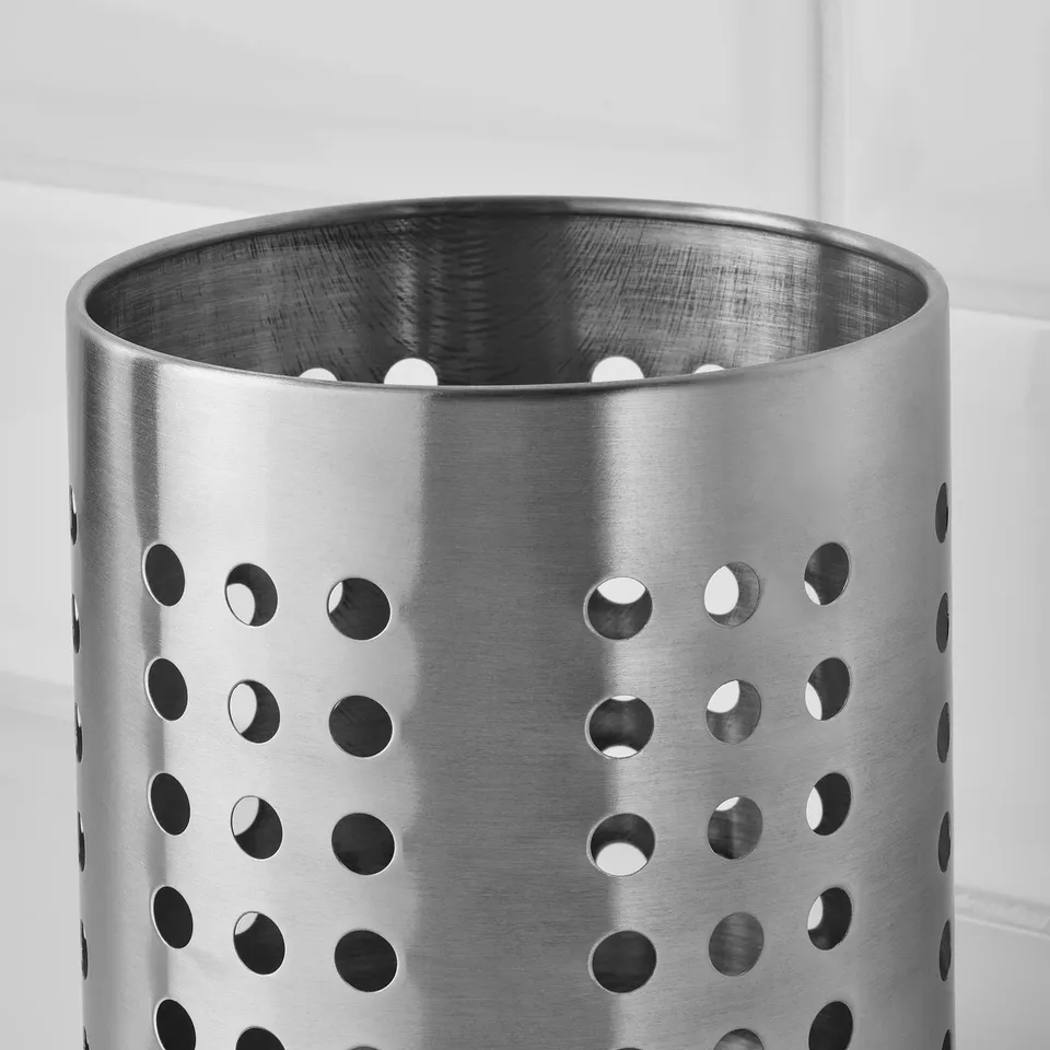 Stainless steel utensil stand with evenly spaced holes.