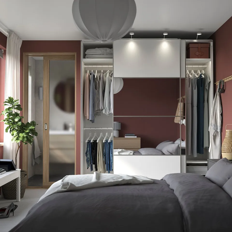 Modern bedroom with white PAX wardrobe, bed, and plant.