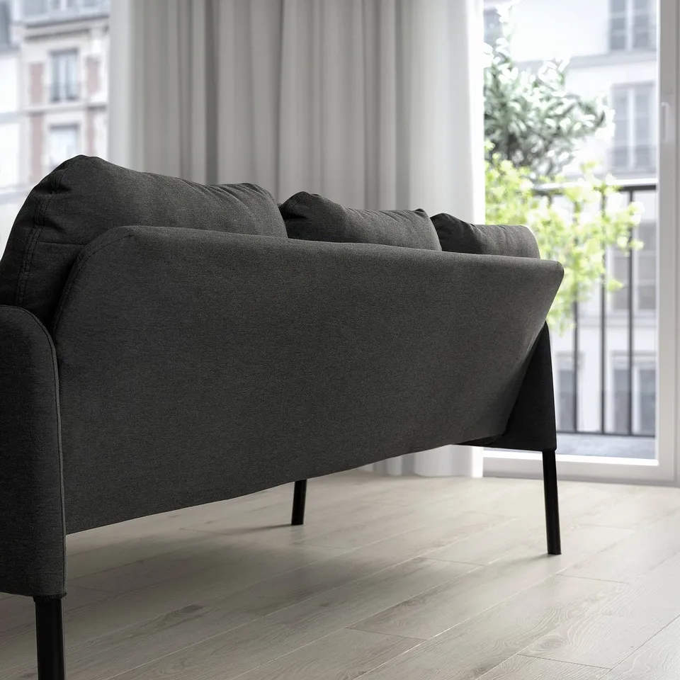 Modern grey GLOSTAD sofa by window, minimalist decor.