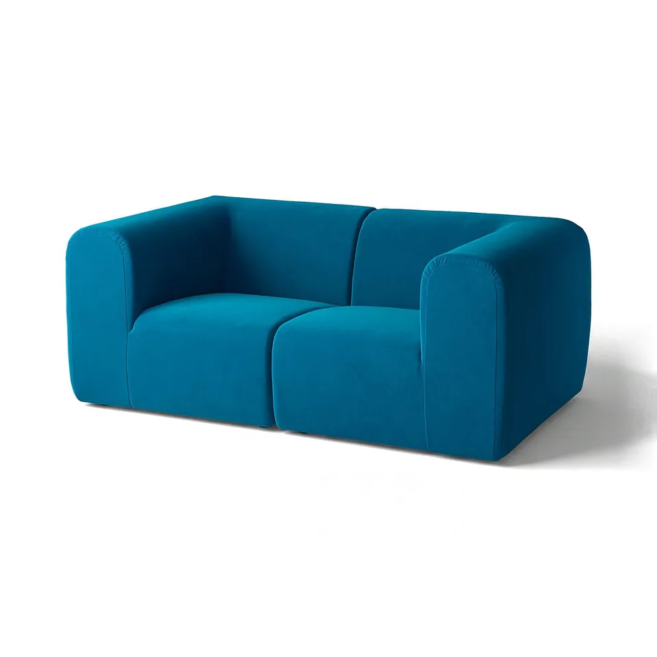 A teal-colored STOCKHOLM 2025 sofa with rounded shapes and a modern design.