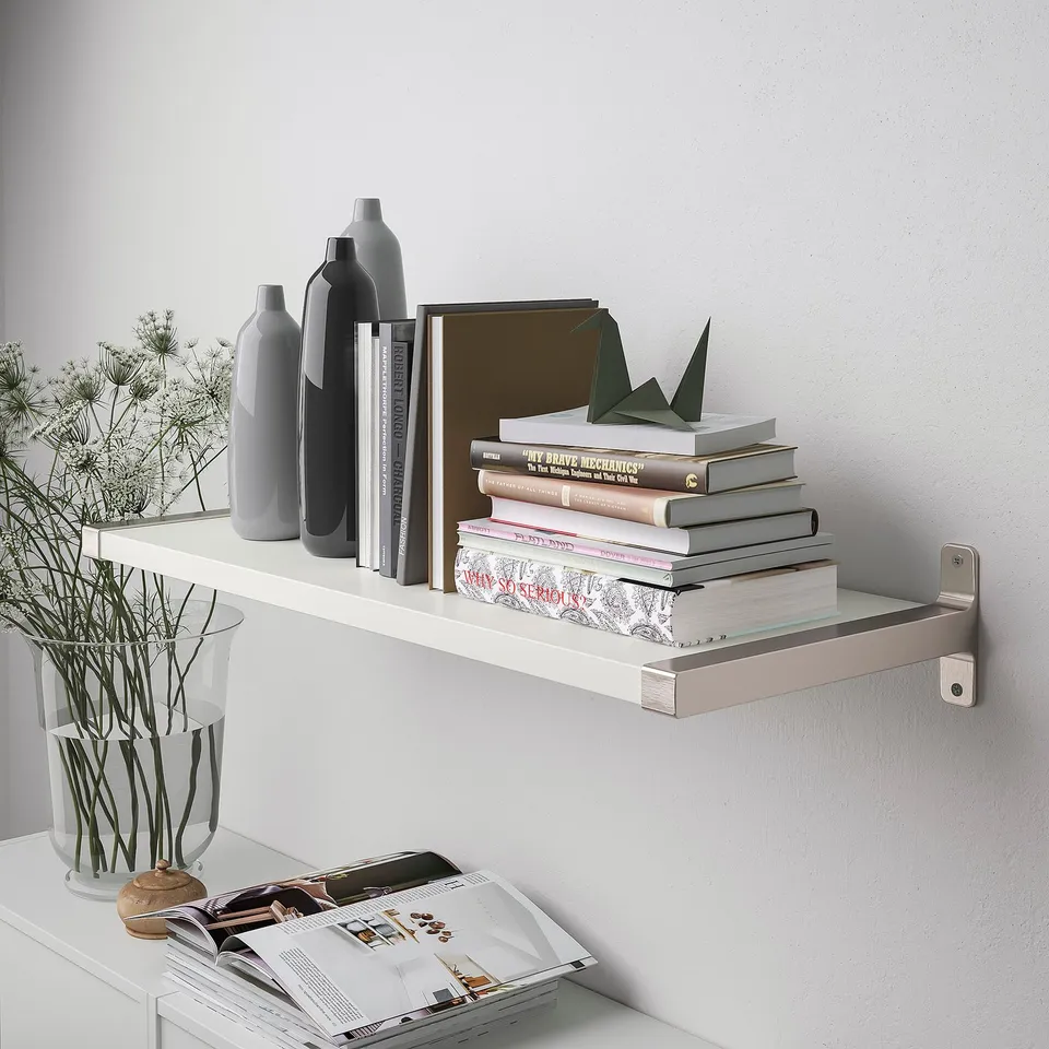 Wall-mounted white shelf with books, vases, and a vase with plants.