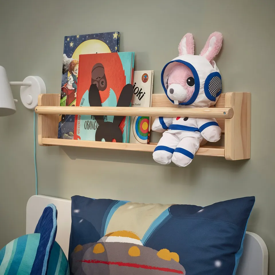 Kids corner with AFTONSPARV astronaut toy, books, & pillows.