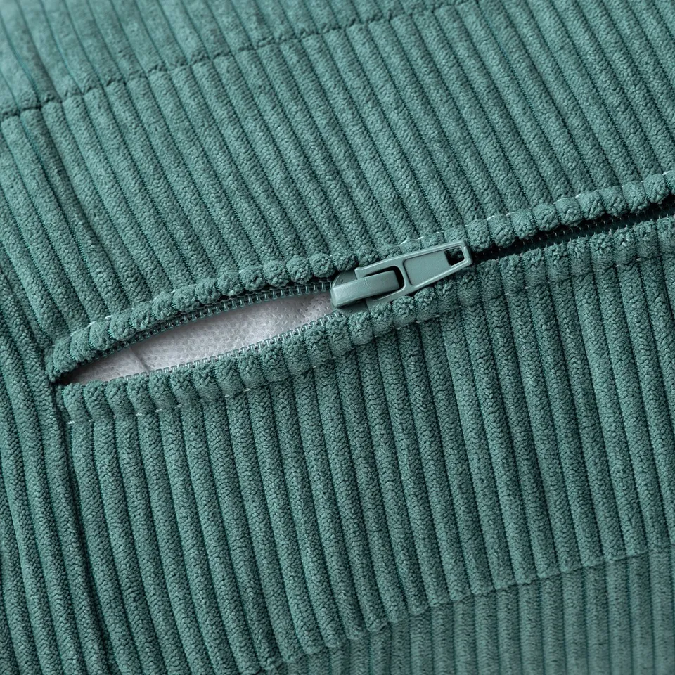 Close-up of green corduroy fabric with a smooth, shiny zip, showcasing textured, high-quality material.