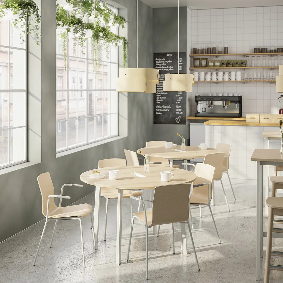 Modern café with wooden tables, light chairs, chalkboard menu, and large windows. Bright and airy.
