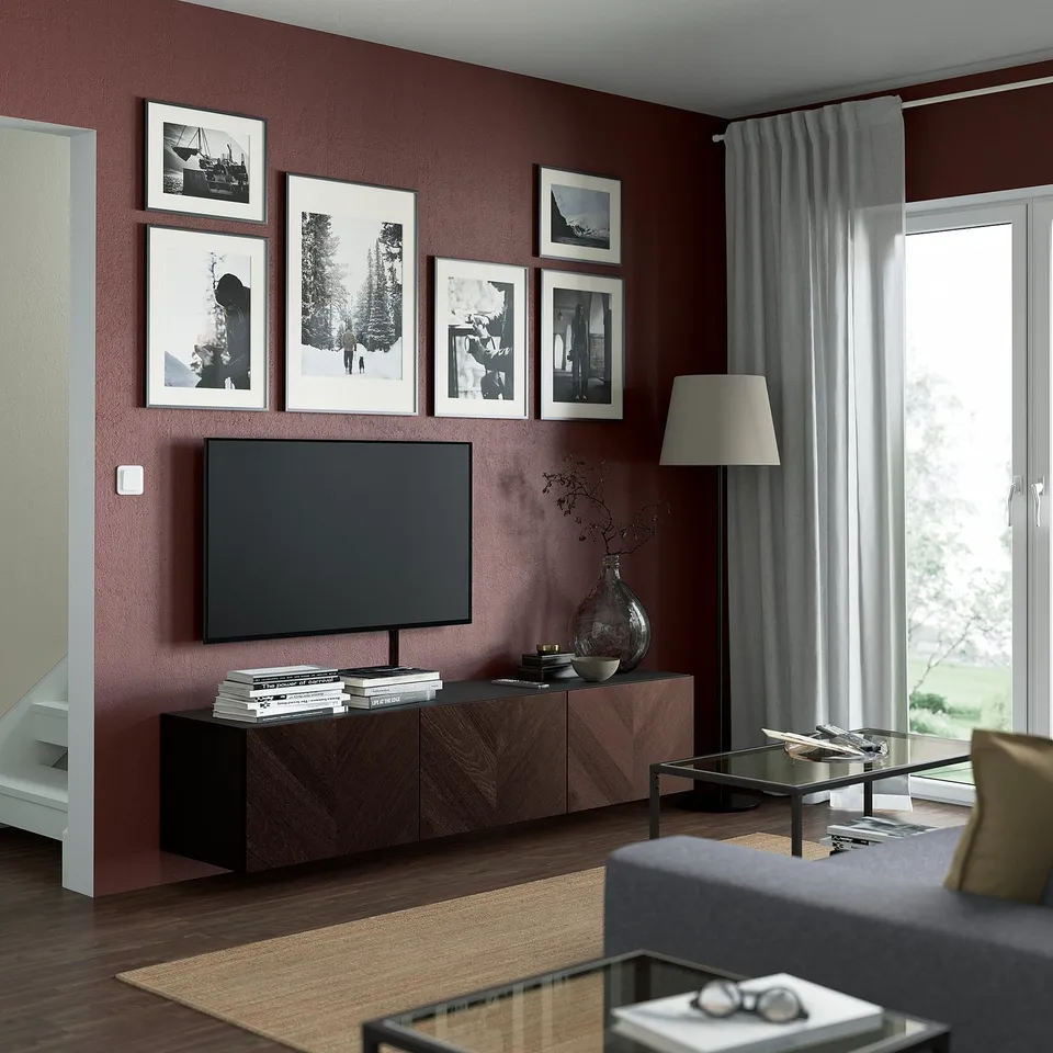 Modern living room with BESTÅ tv bench in dark wood, flat-screen tv, black frames, grey curtains, and glass coffee table.
