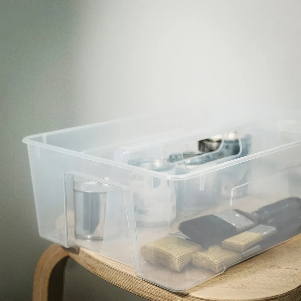Transparent plastic organiser insert with two compartments, placed inside a wooden drawer, providing efficient storage.