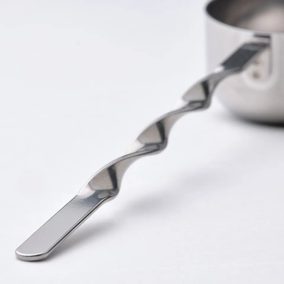 Stainless steel scoop with wavy handle rests on white surface, showcasing its sturdy and sleek design.
