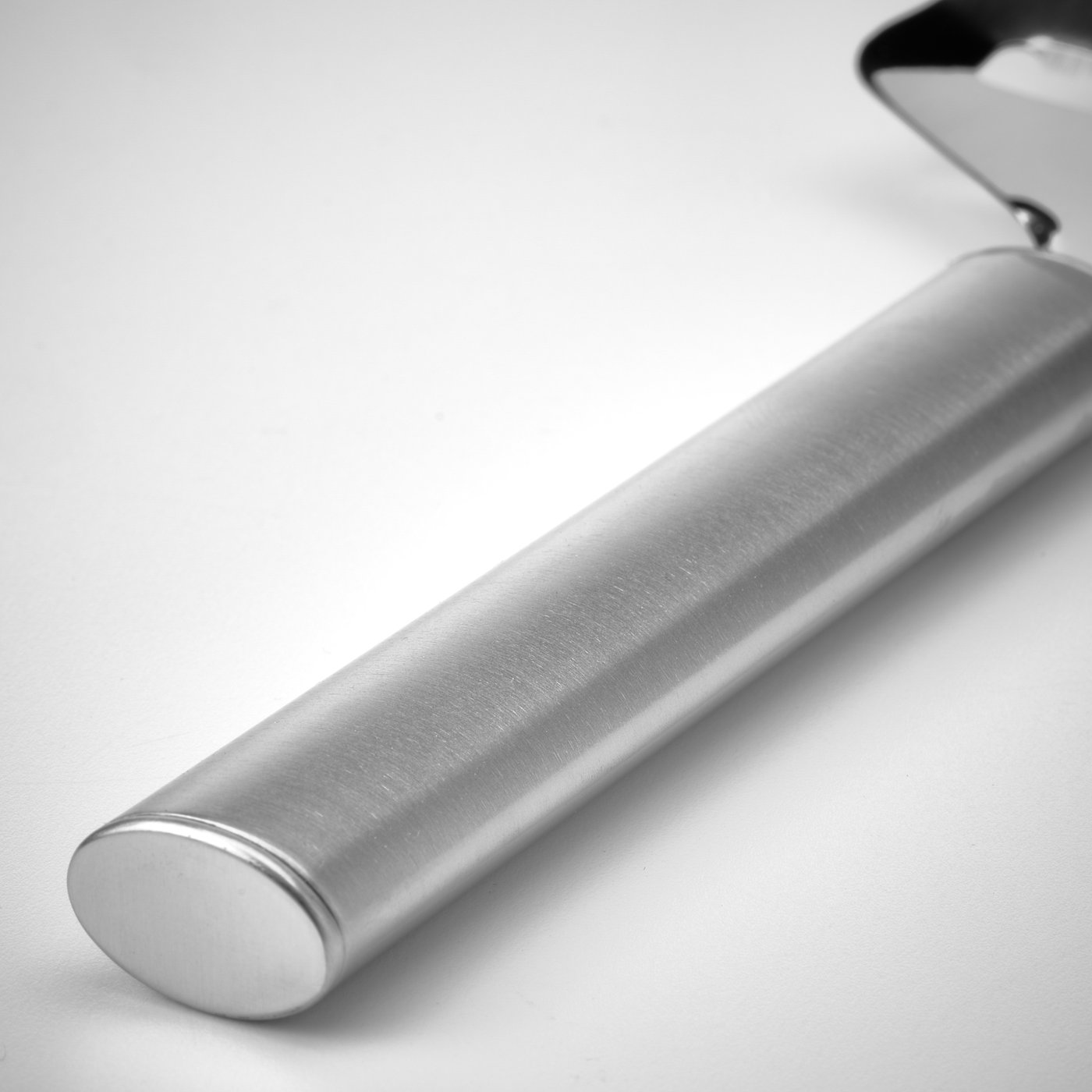 Silver stainless steel cheese slicer, lying diagonally, reflecting light.