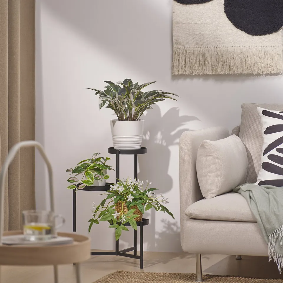Modern living room with FEJKA plant, armchair, and side table with cups.