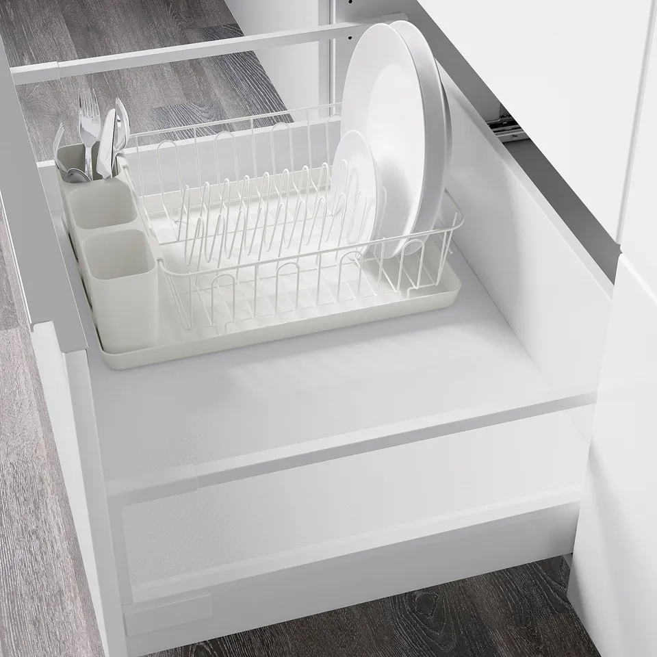 White dish drainer with removable tray inside cabinet to collect water.