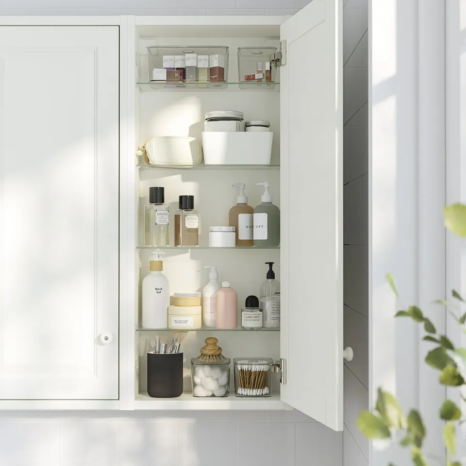 Open white bathroom cabinet with glass shelves holding toiletries.