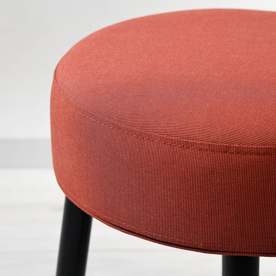 A modern, orange upholstered stool with sleek black metal legs, showcasing high-quality fabric and sturdy design.