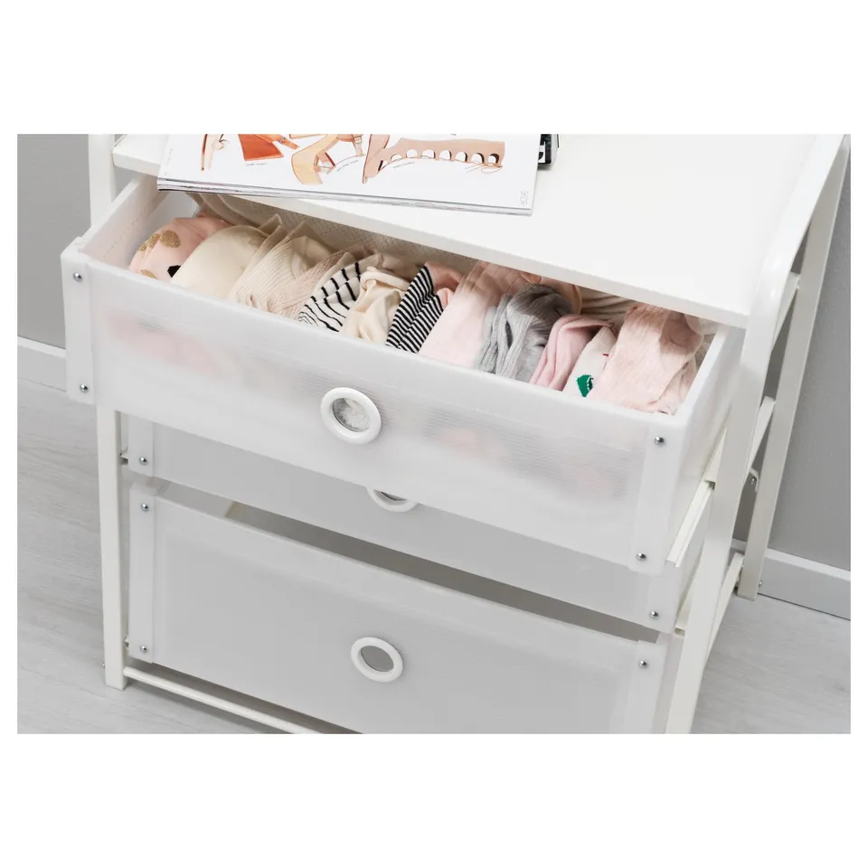 White chest drawer open, showing neatly folded pink and striped clothes. Drawer has circular handle.