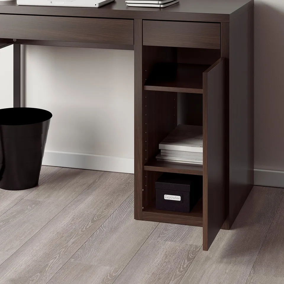 A dark brown desk with a shelf unit featuring adjustable shelves and a cable outlet, situated in a room with wooden flooring.