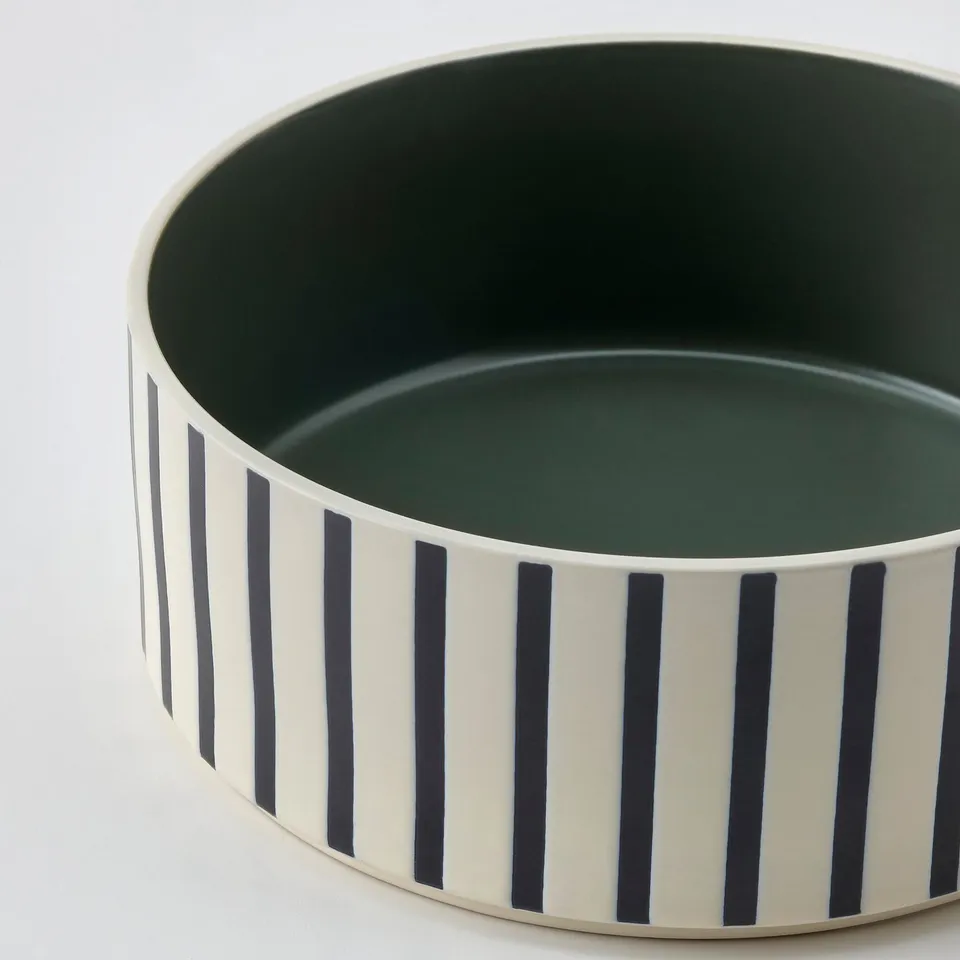 Black and white striped pet bowl, durable stoneware with green interior.