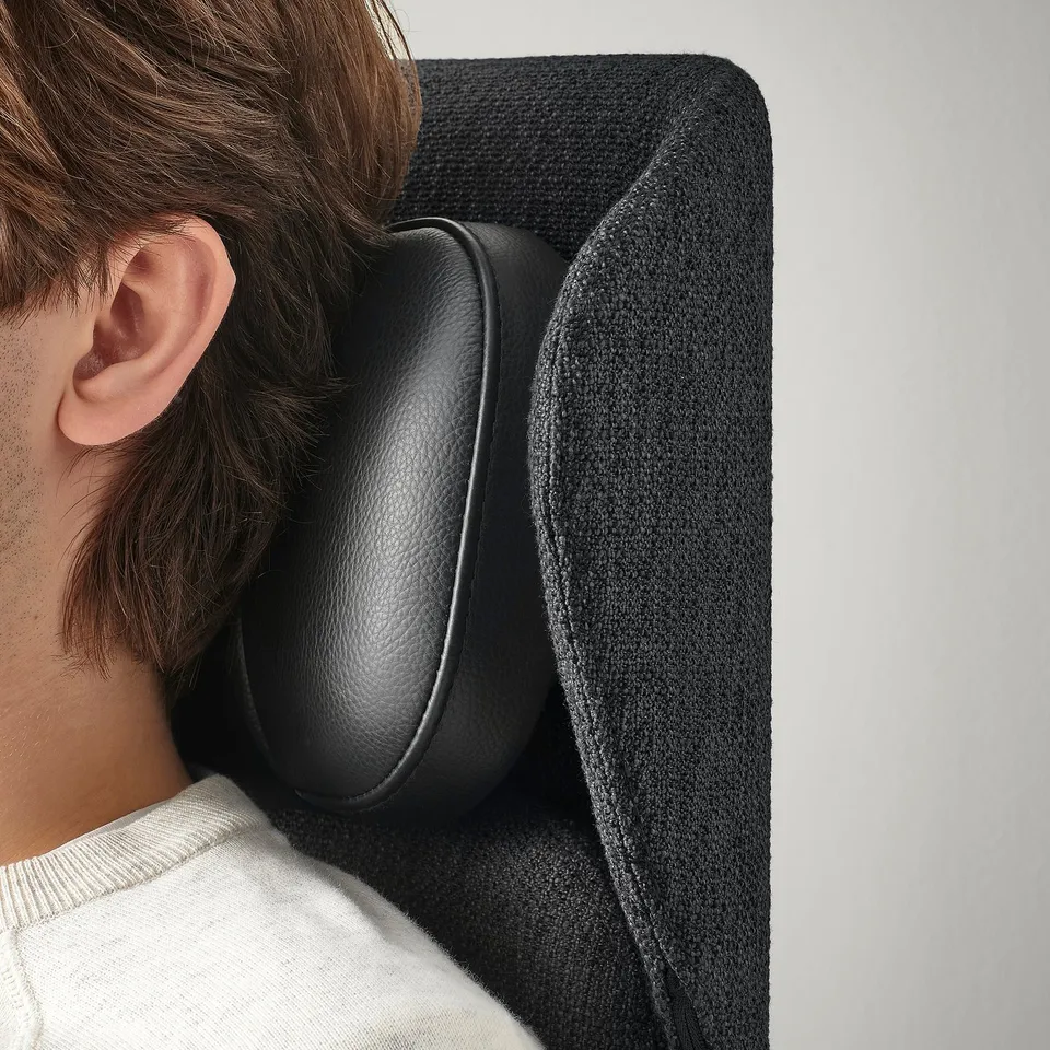 Person sits in ergonomic office chair with adjustable headrest.