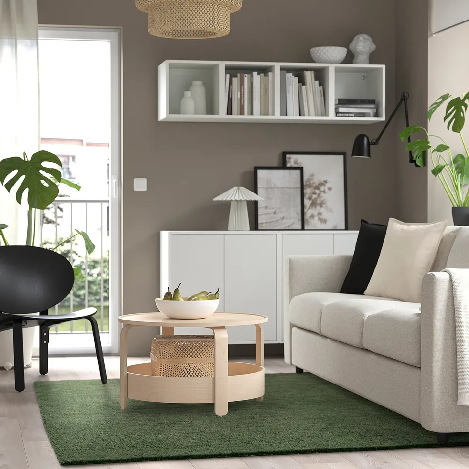 Modern living room with STOENSE green rug, white sofa, wooden coffee table, and wall decorations.