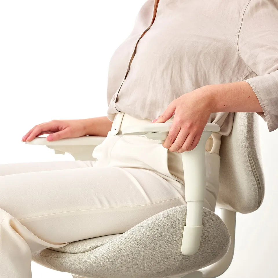 A person adjusting an ergonomic office chair armrest, emphasising comfort and customization.