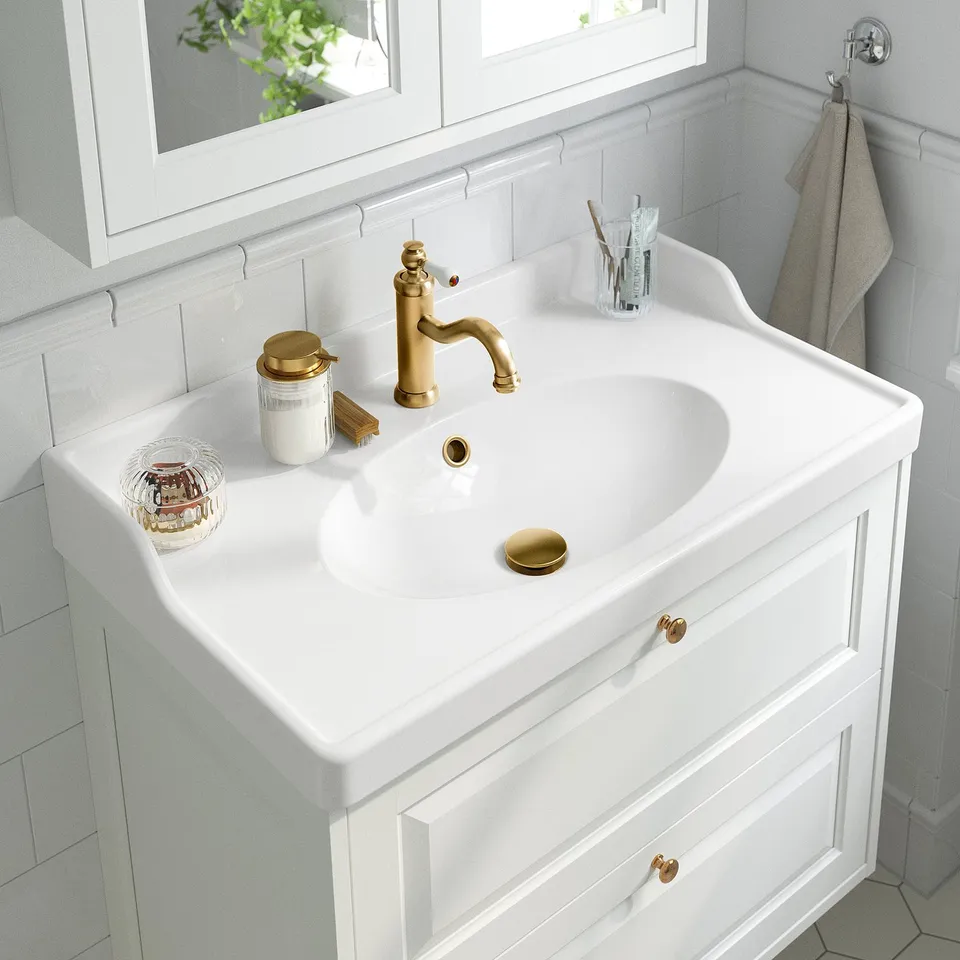 Modern bathroom sink with gold tap and cold start function, ensuring energy savings and convenience.