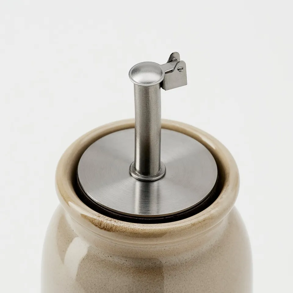 Stoneware jar with stainless steel lid spout, silicone seal for secure fit.