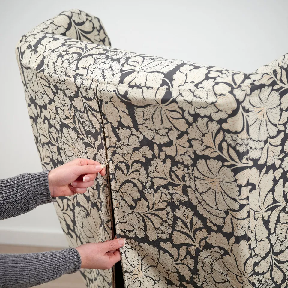 Person adjusting zip on decorated chair cover.