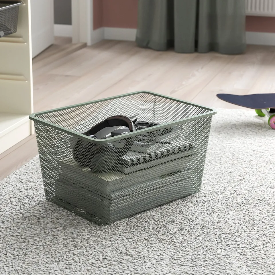 Mesh storage bin on carpet, holds small items, part of TROFAST system.