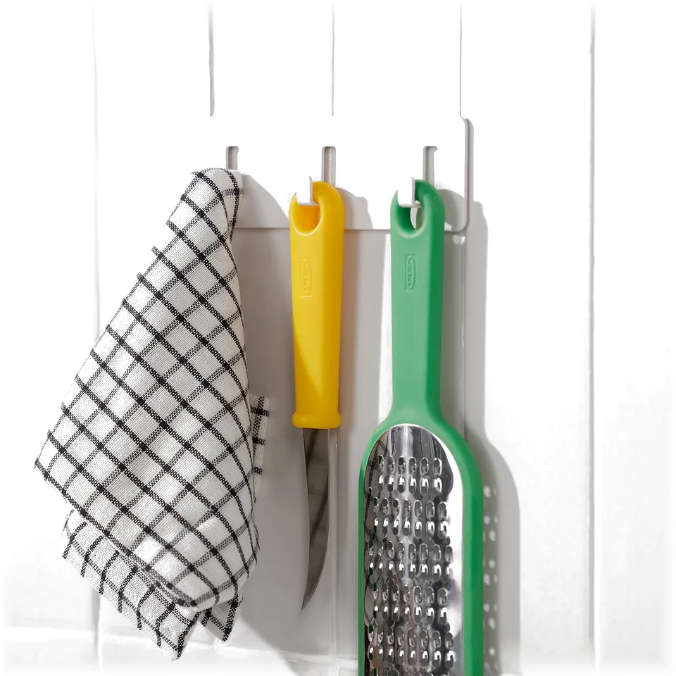 White wall-mountable rack with three hooks, holding a towel, yellow, and green kitchen utensils, efficiently organising small items.