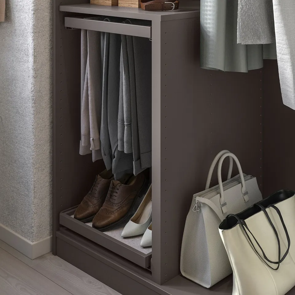 Organised closet with hanging grey clothes, brown shoes, and white bags. KOMPLEMENT storage unit in dark grey.
