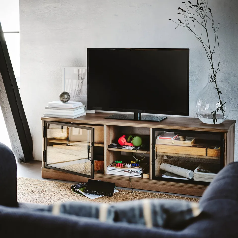Modern living room with wooden tv stand, flat screen tv, decorative items, and blue sofa.