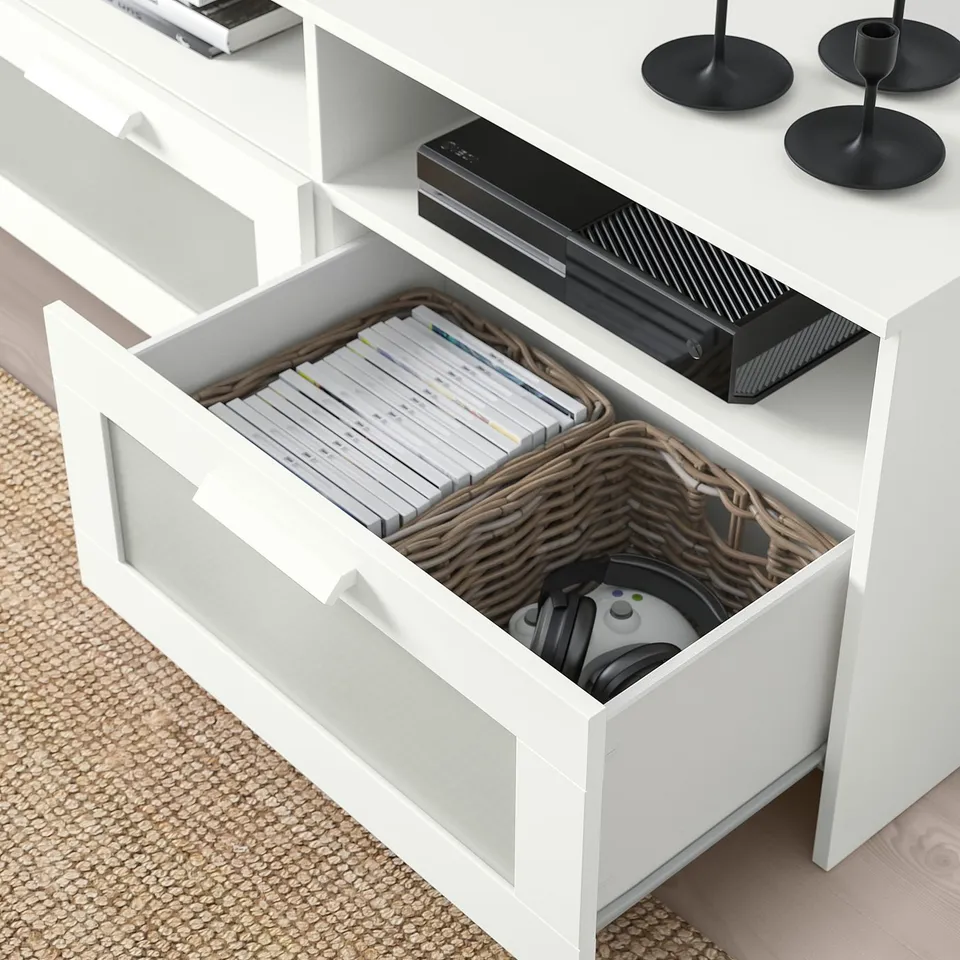 White tv stand with open drawer showing dvds, remote, and basket.
