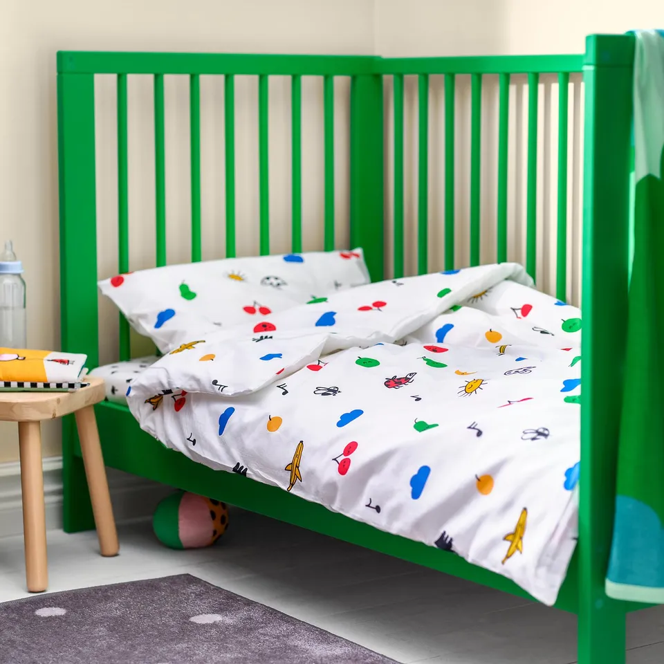 Bright green GRÖNFINK crib with colourful bug-themed bedding. Soft, comfy, and sized perfectly for the crib.