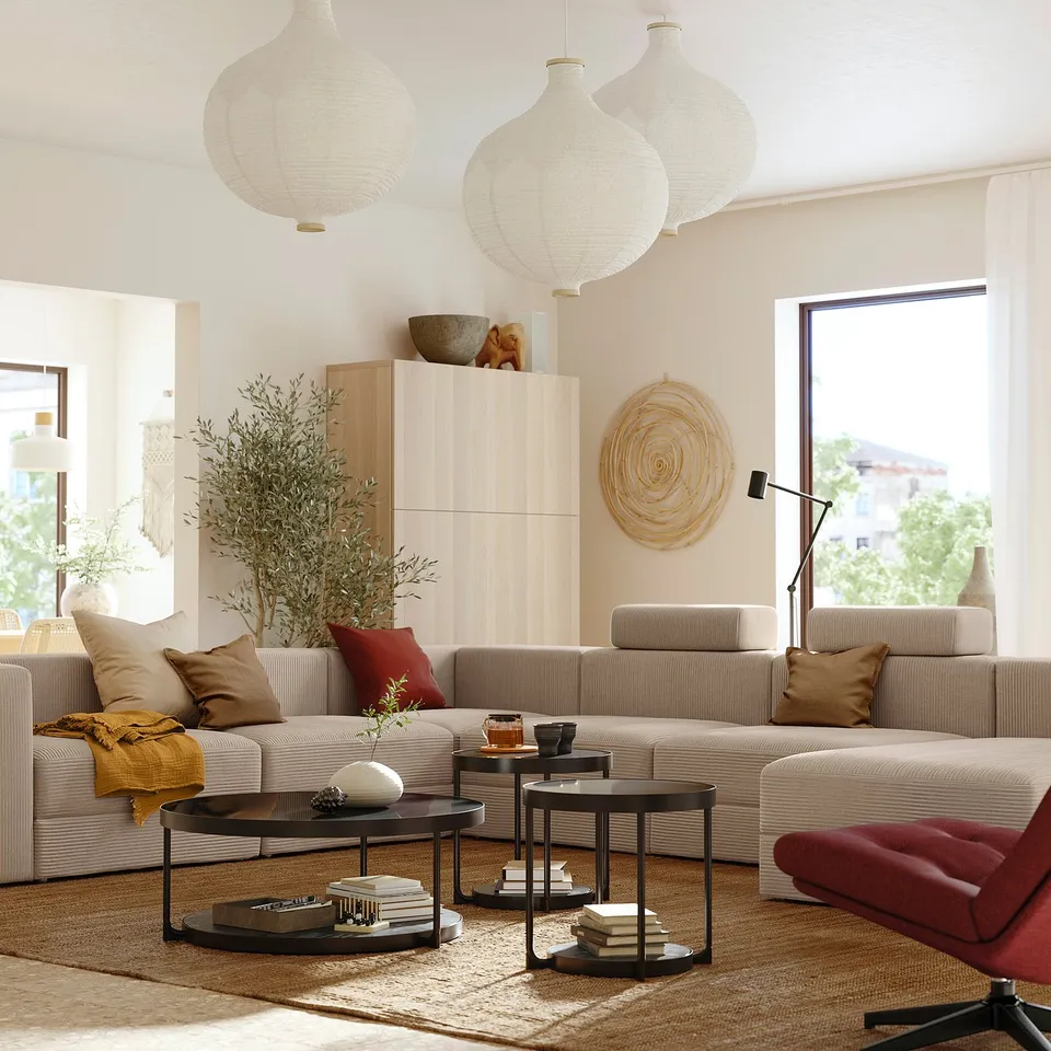 Modern living room with JÄTTEBO beige modular sofa, black coffee tables, red sofa chair, woven art, large window, and hanging lamps.