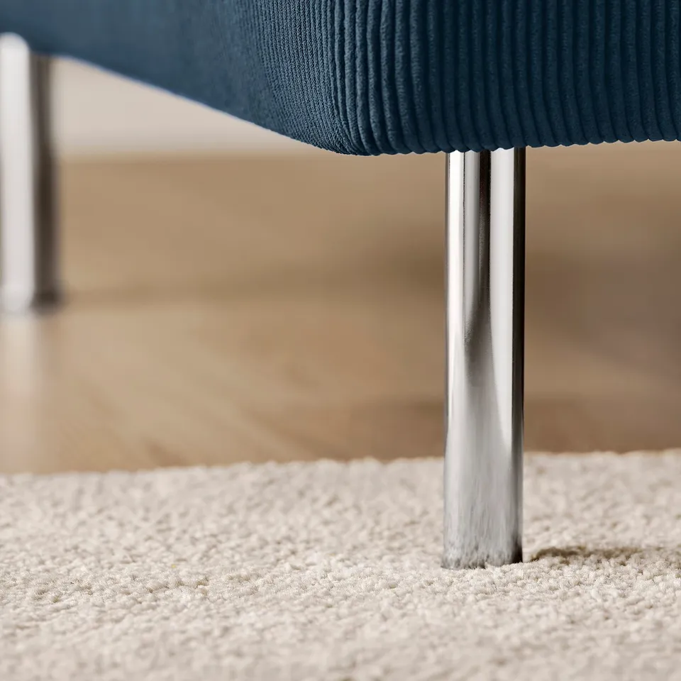 Modern chair with sleek metal legs, plush blue seat, on a textured rug.