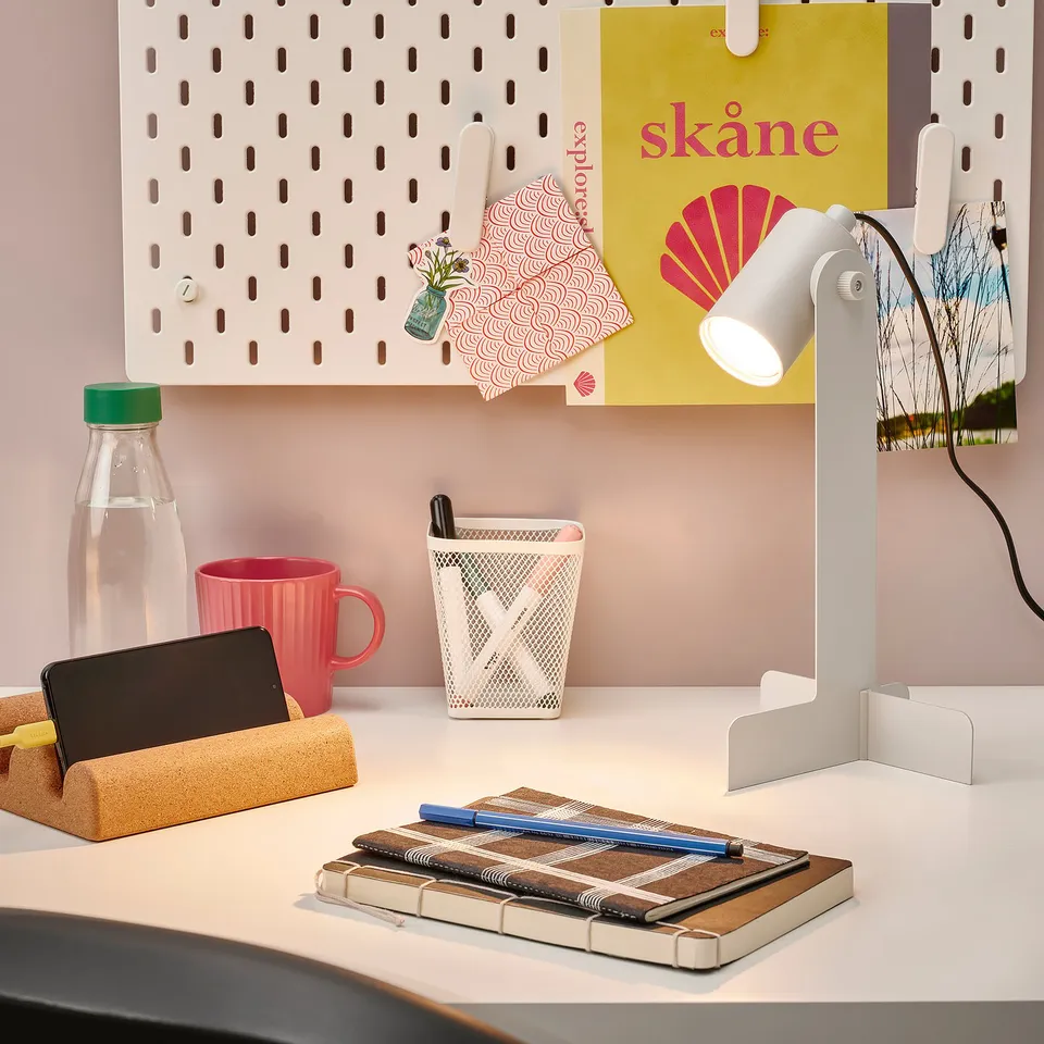 FLOTTILJ desk lamp on desk with notebooks and mug.