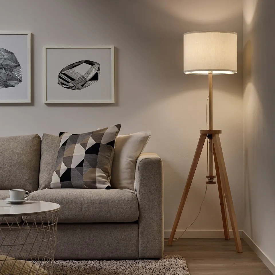 LAUTERS lamp in living room, wood base, white shade, beside grey sofa.