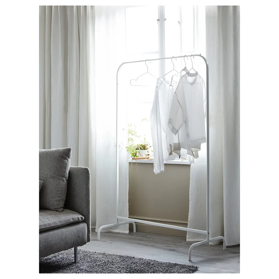 Minimalist room: MULIG rack, clothes, armchair, plant, window, wooden floor.