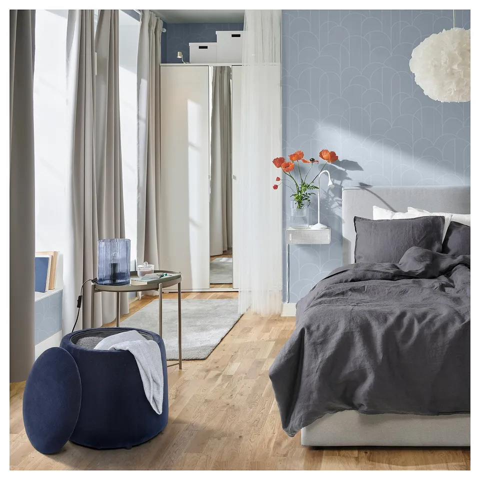 Bedroom with JÄRRESTAD pouffe, storing items. Dark bedding, mirror, wooden floor, modern decor.