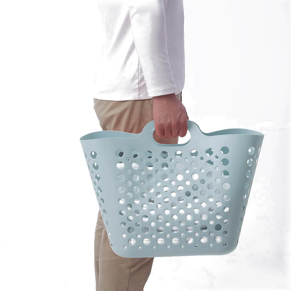 Person holding a blue perforated laundry basket by the handle.