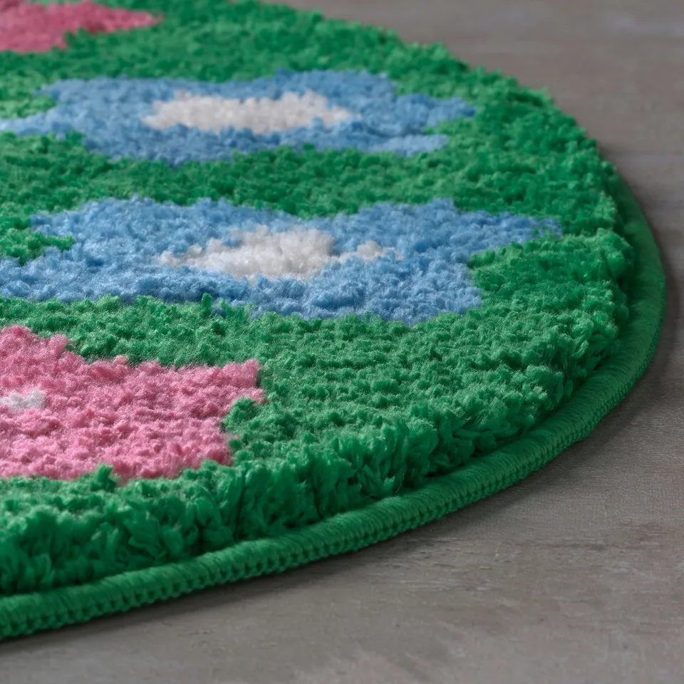 Round, soft bath mat featuring green, blue, and pink flower patterns. Has a thick, plush texture for comfort.