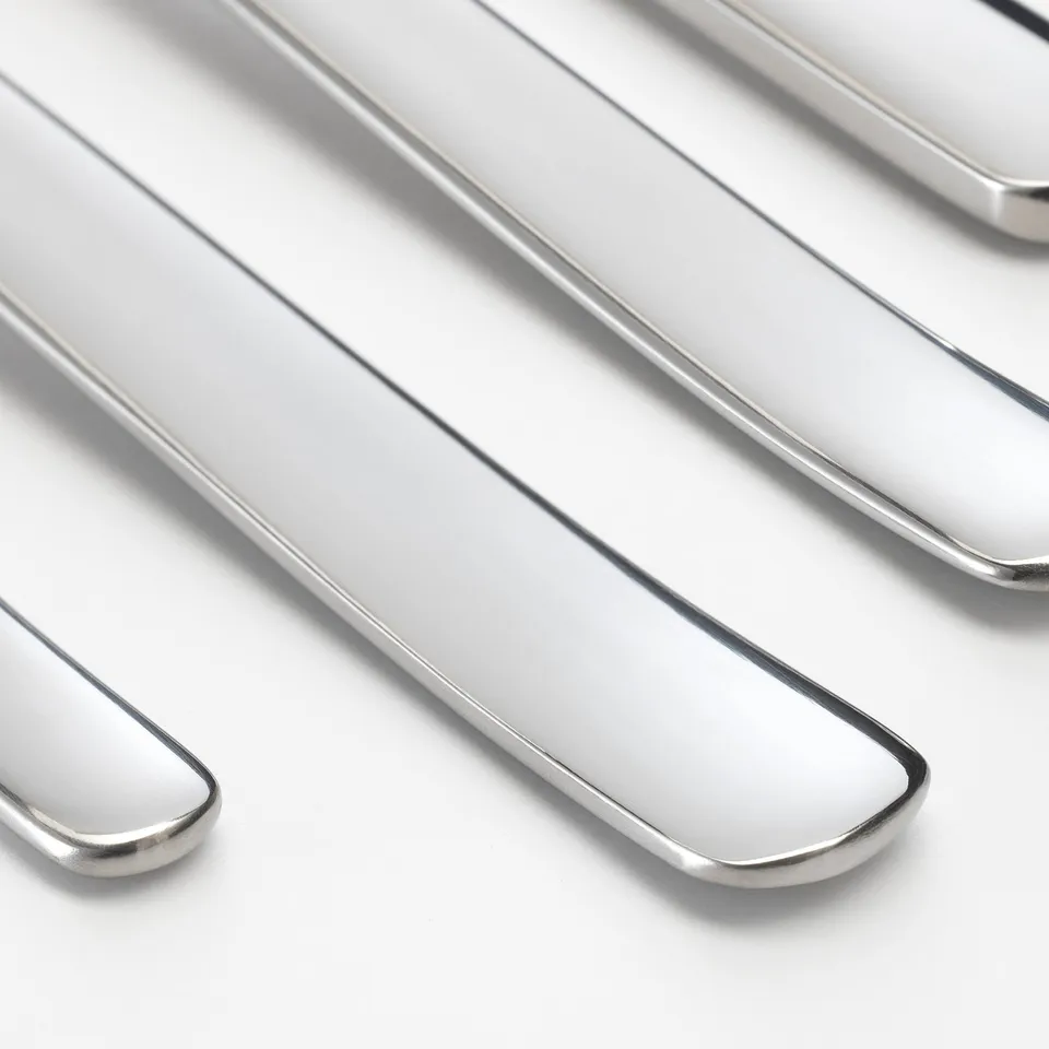 Polished silverware neatly arranged, showcasing smooth, reflective surfaces and sleek edges.