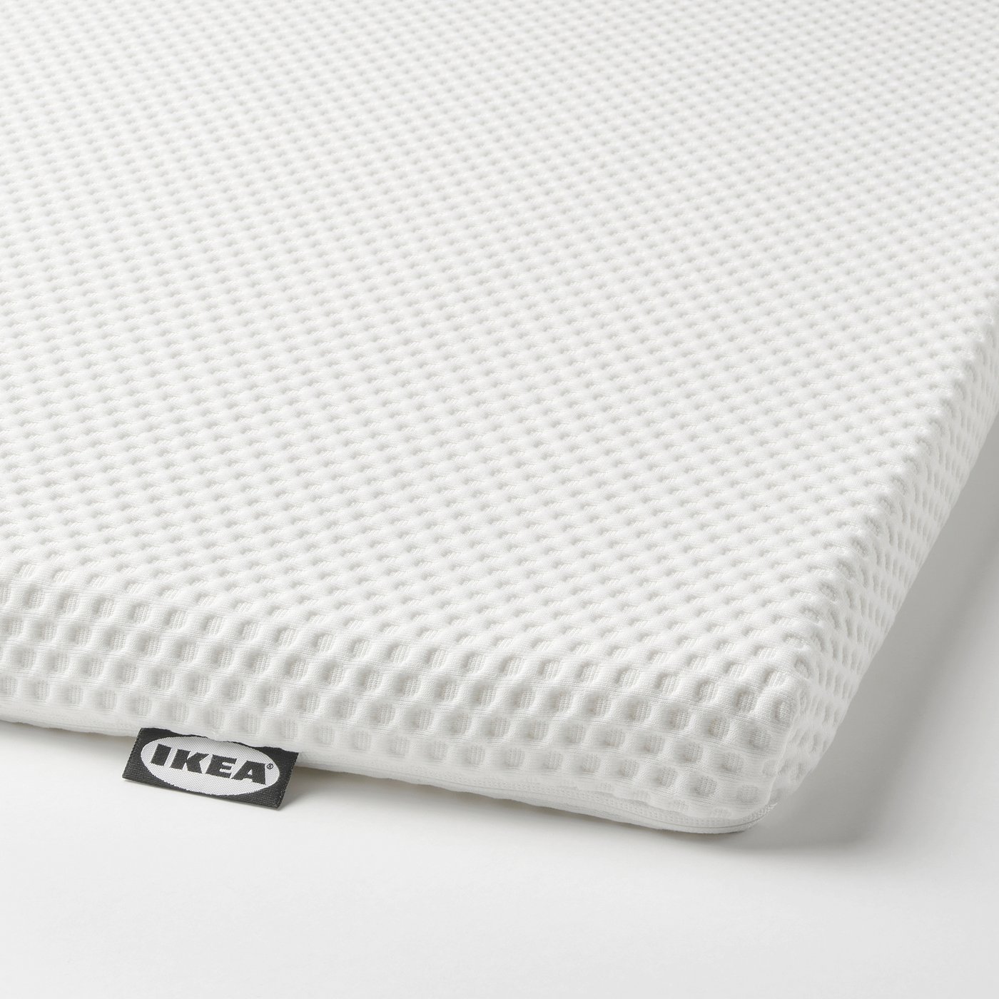 White foam mattress topper with ikea tag, smooth surface for comfort.