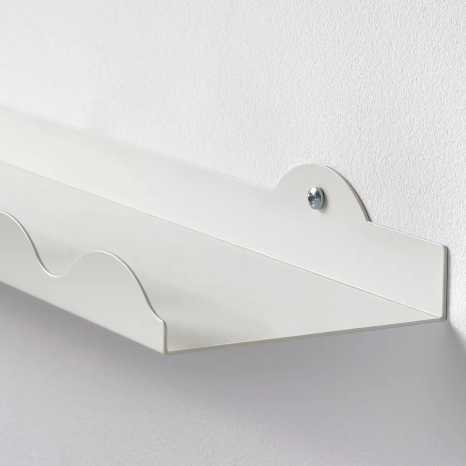 White wall-mount picture ledge with smooth edges, securely attached to light grey wall. Elegant and sturdy design for displaying photos or art.