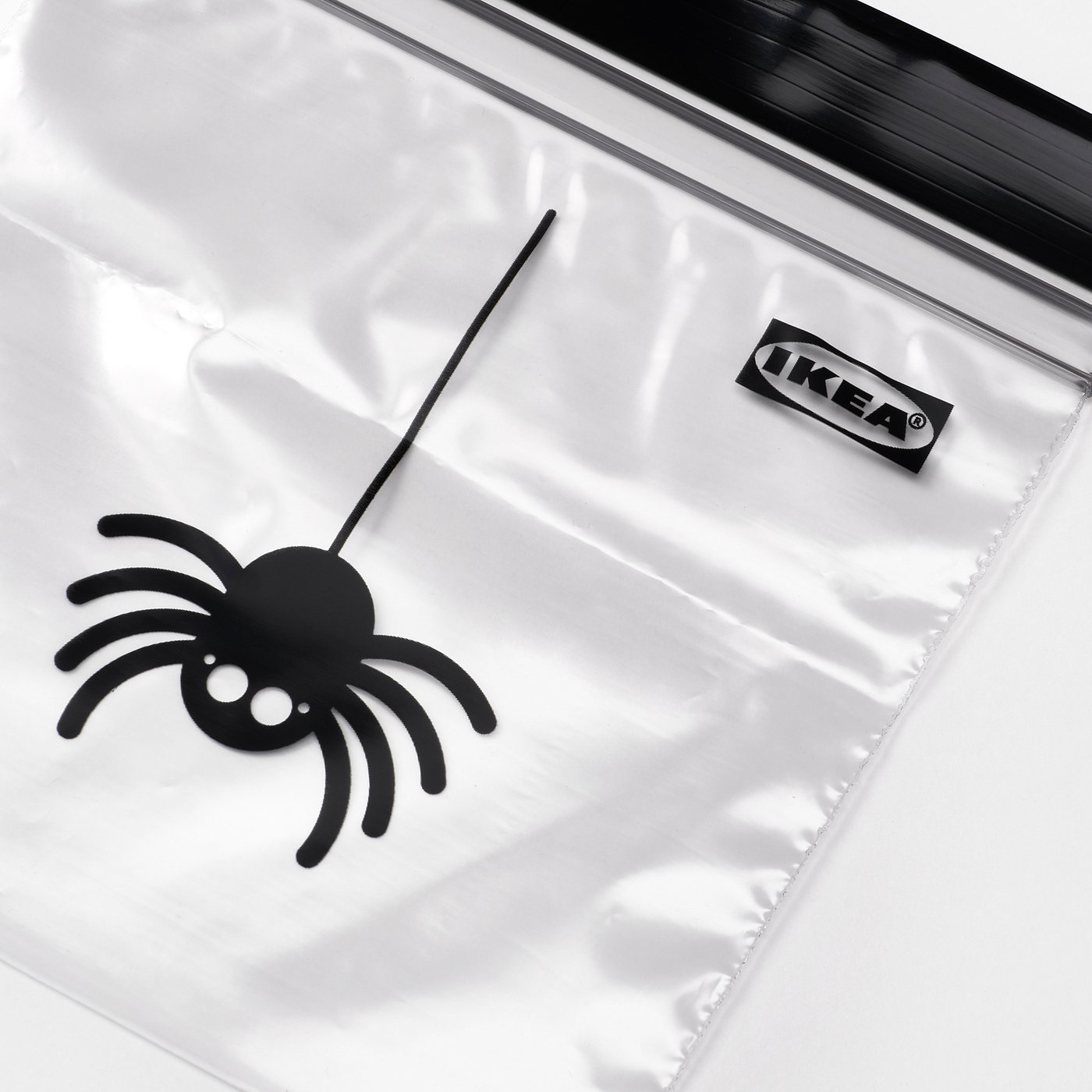 Clear plastic bag with black spider decoration, IKEA label.