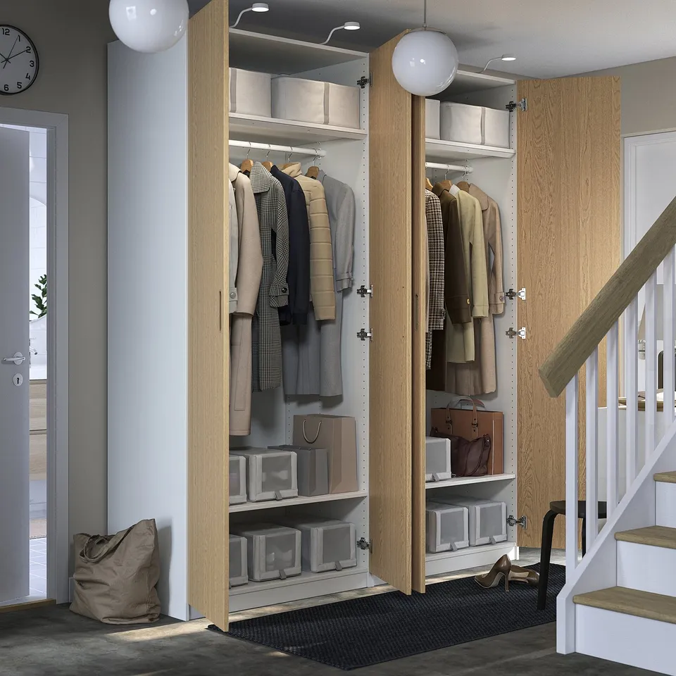 Modern closet with open doors, clothes and boxes. Near staircase, clock on wall.