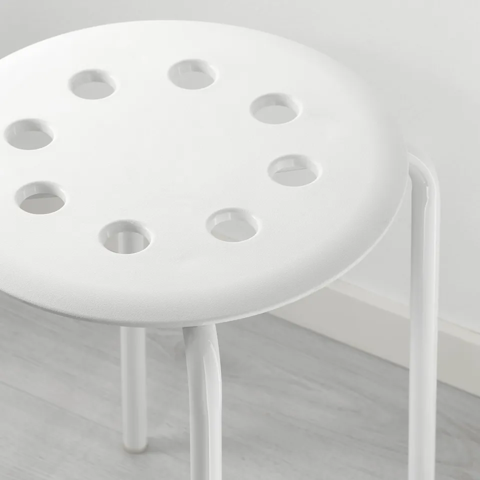 Small white stool with seven holes on circular seat, supported by three slim legs, showcasing quality craftsmanship and modern design.