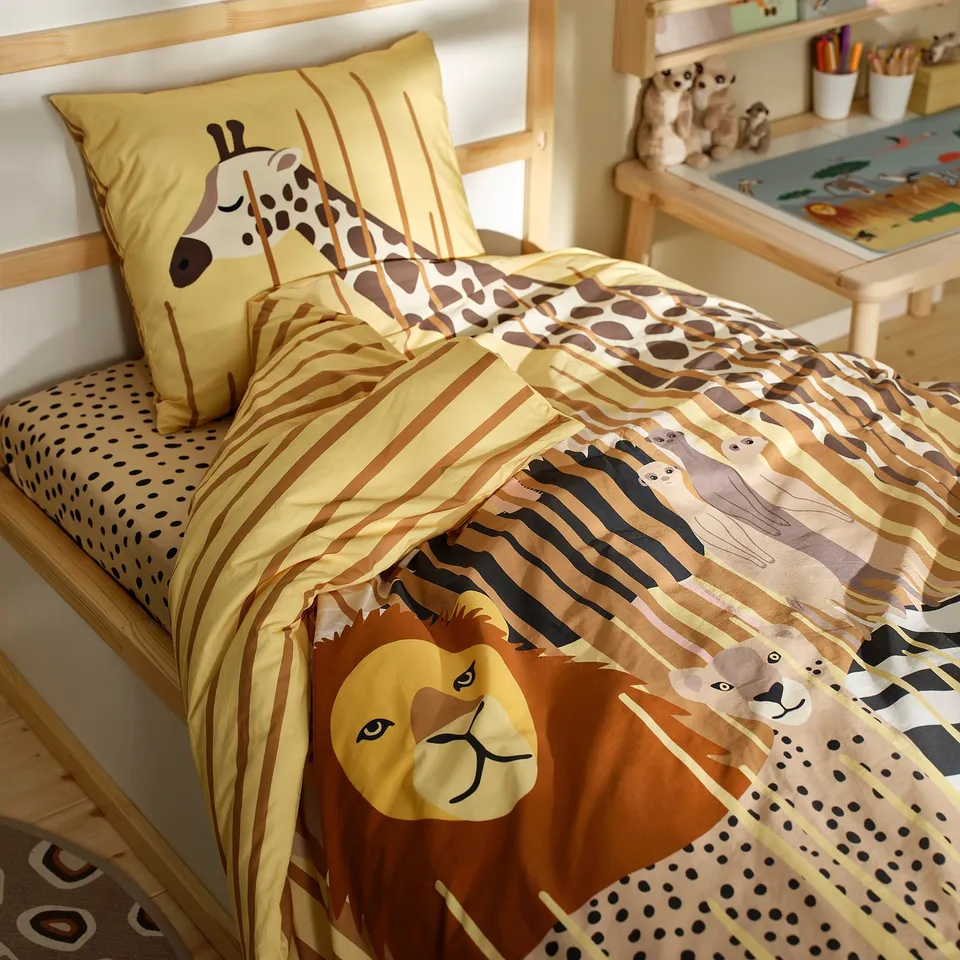 SANDLÖPARE kids bedding set with giraffe pillow and safari duvet, lions, zebras, grass patterns. Bright yellow and brown, neat room with desk, toys.