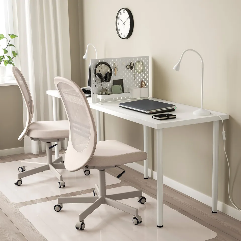 Home office setup with SKÅDIS white desk divider, chair, & accessories. Pegboard organised with office supplies. Desk lamp & potted plant.
