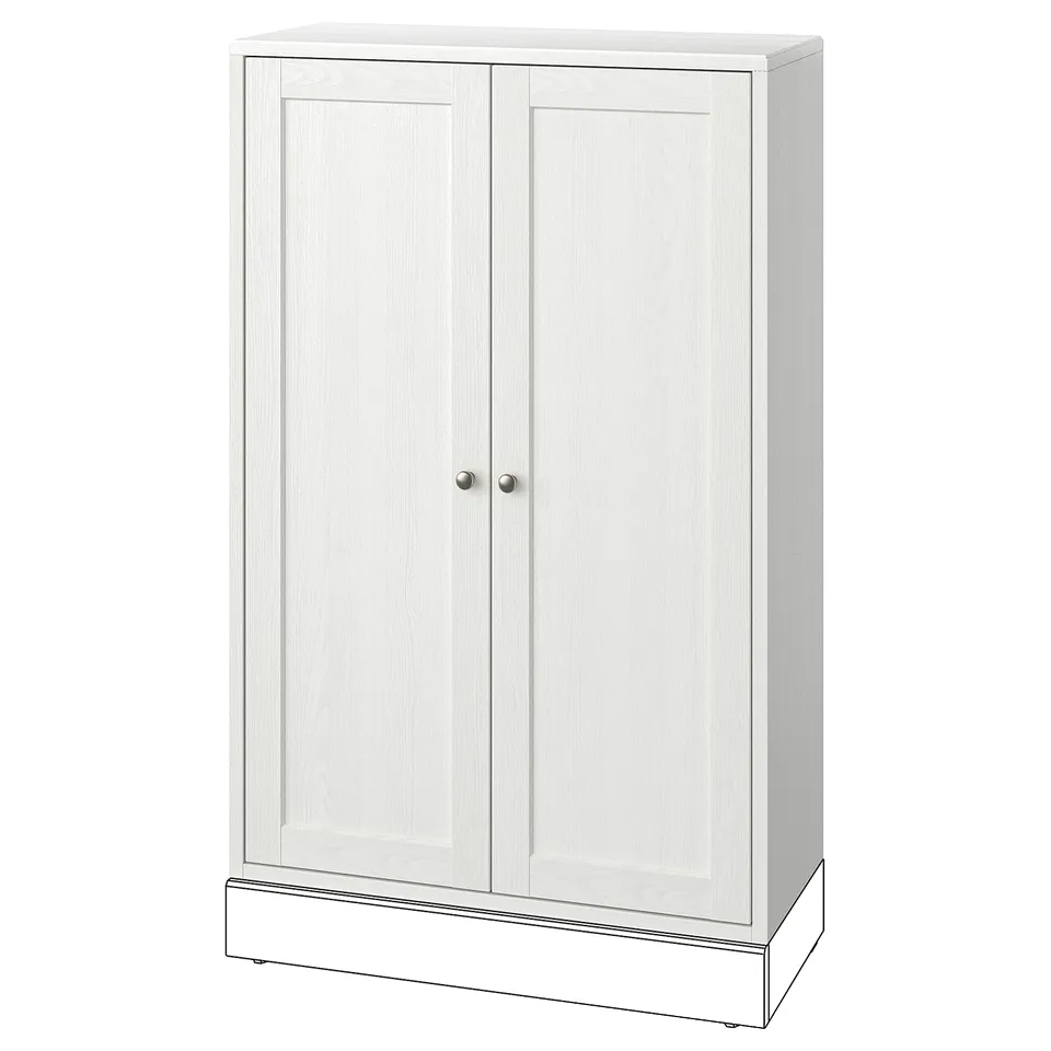 A HAVSTA white wooden cabinet, made of solid pine with a brushed finish. It has two doors with round knobs and a simple, rustic design.