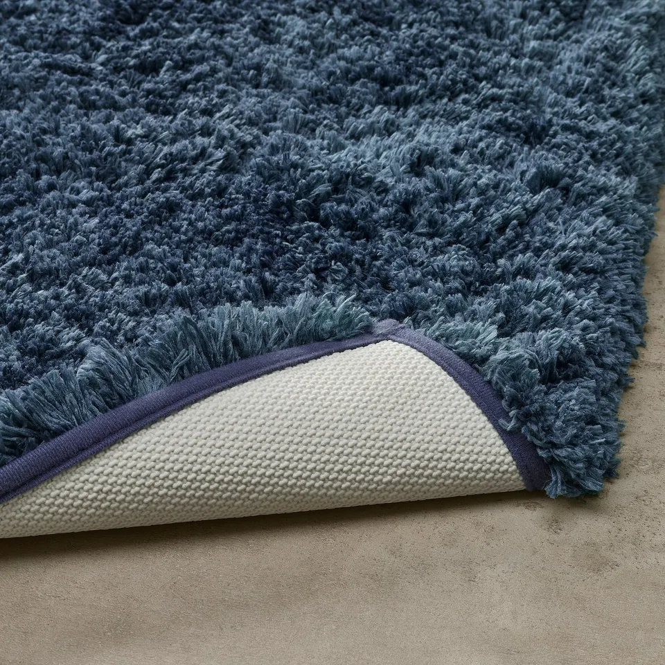 Pile of soft blue bath mat, showing plush top and textured latex backing.